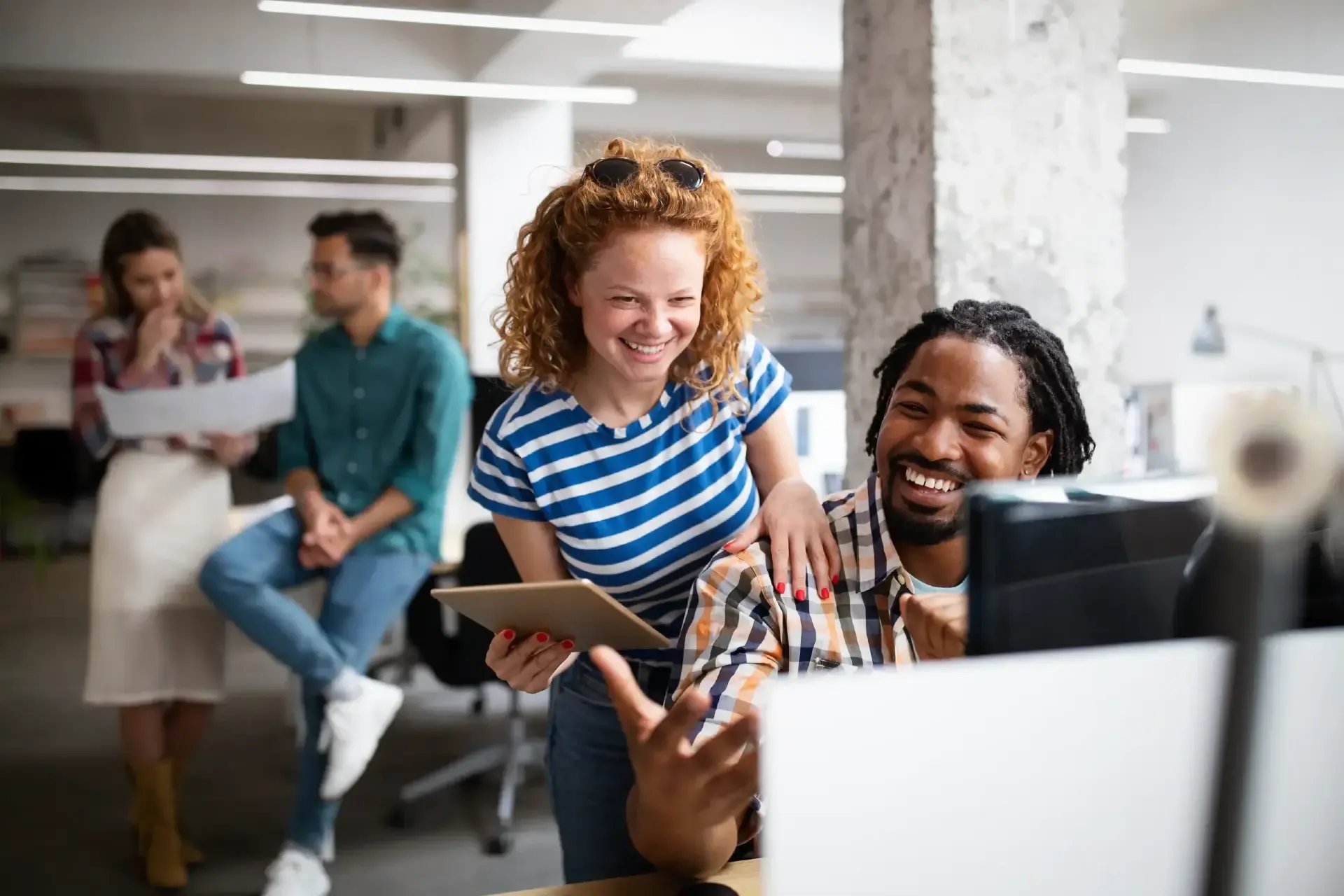 2 office workers smiling using laptops