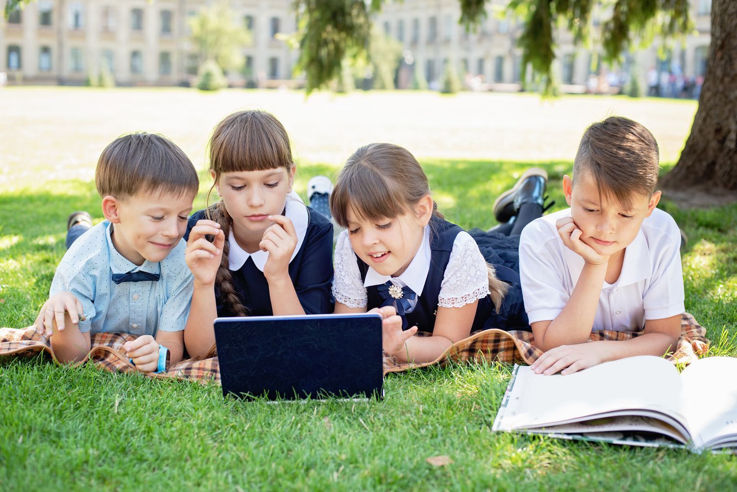 School children on laptops outside on campus